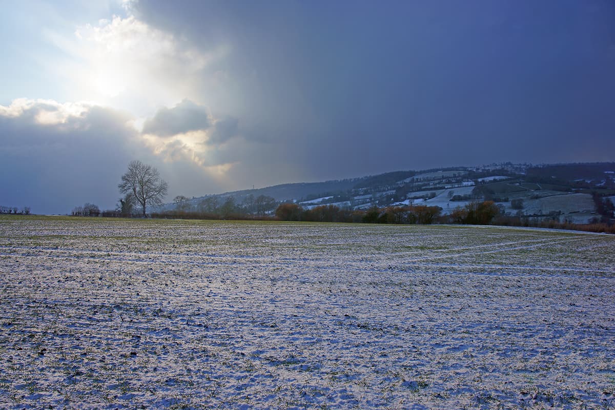 A stormy sky at sunset looking across open fields towards Whiteshill and along the Stroud Valley and the Cotswold escarpment.